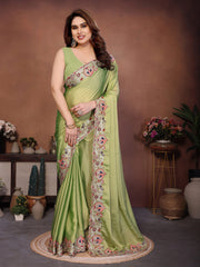 Woman wearing a green saree with floral patterns in a decorated indoor setting