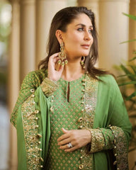 Woman wearing a green embroidered outfit with gold details indoors.