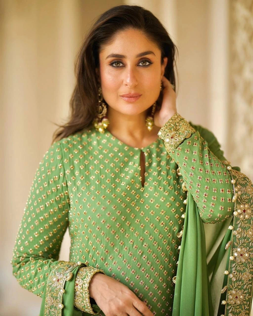 Woman wearing a green embroidered traditional outfit with gold details.