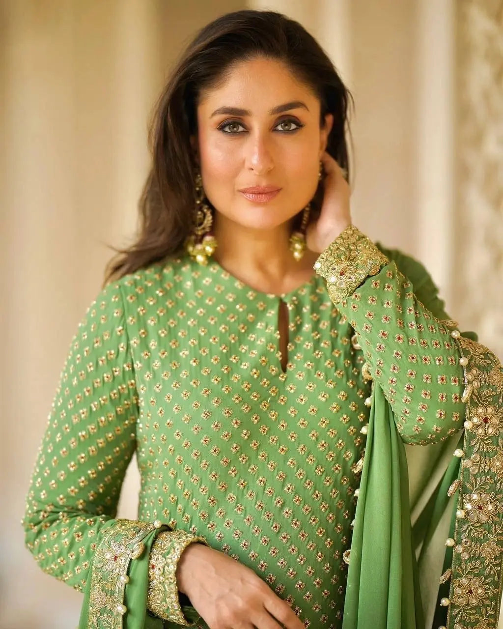 Woman wearing a green embroidered traditional outfit with gold details.