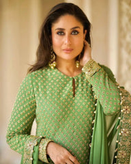 Woman wearing a green embroidered traditional outfit with gold details.
