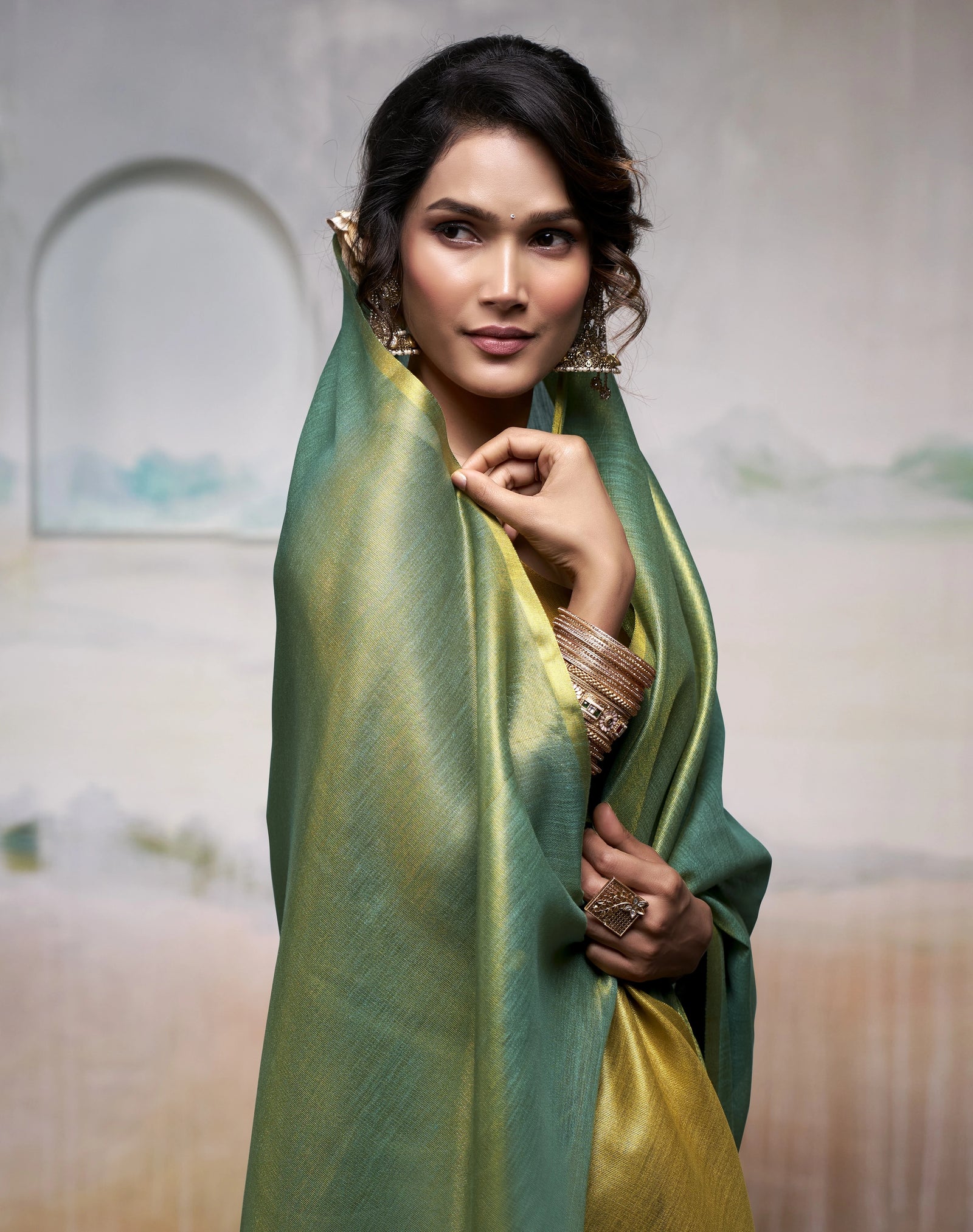 Woman wearing a green and yellow saree with a blurred background