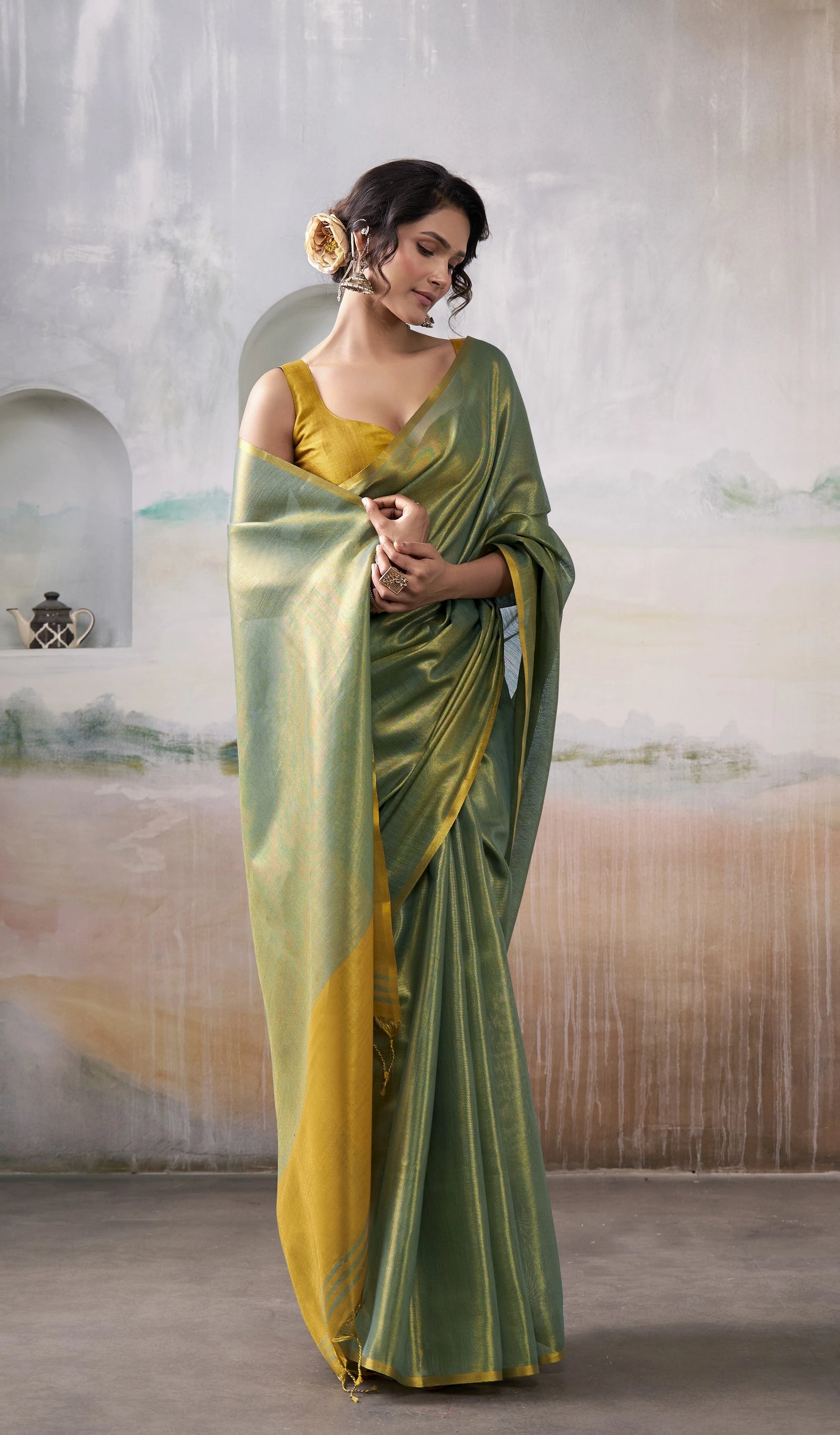 Woman wearing a green and yellow saree in an indoor setting