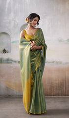 Woman wearing a green and yellow saree in an indoor setting