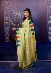 Woman wearing a green saree with a colorful border against a decorative blue and purple background