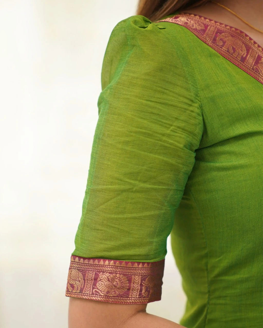 Green saree with purple border on a plain background