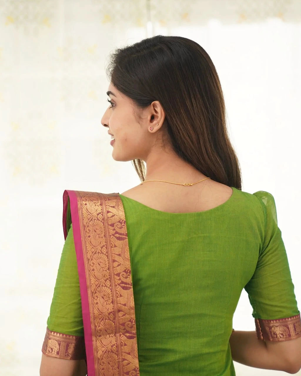 Woman wearing a green saree with a pink blouse against a white background