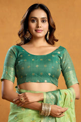Woman wearing a green saree with a matching blouse against a beige background