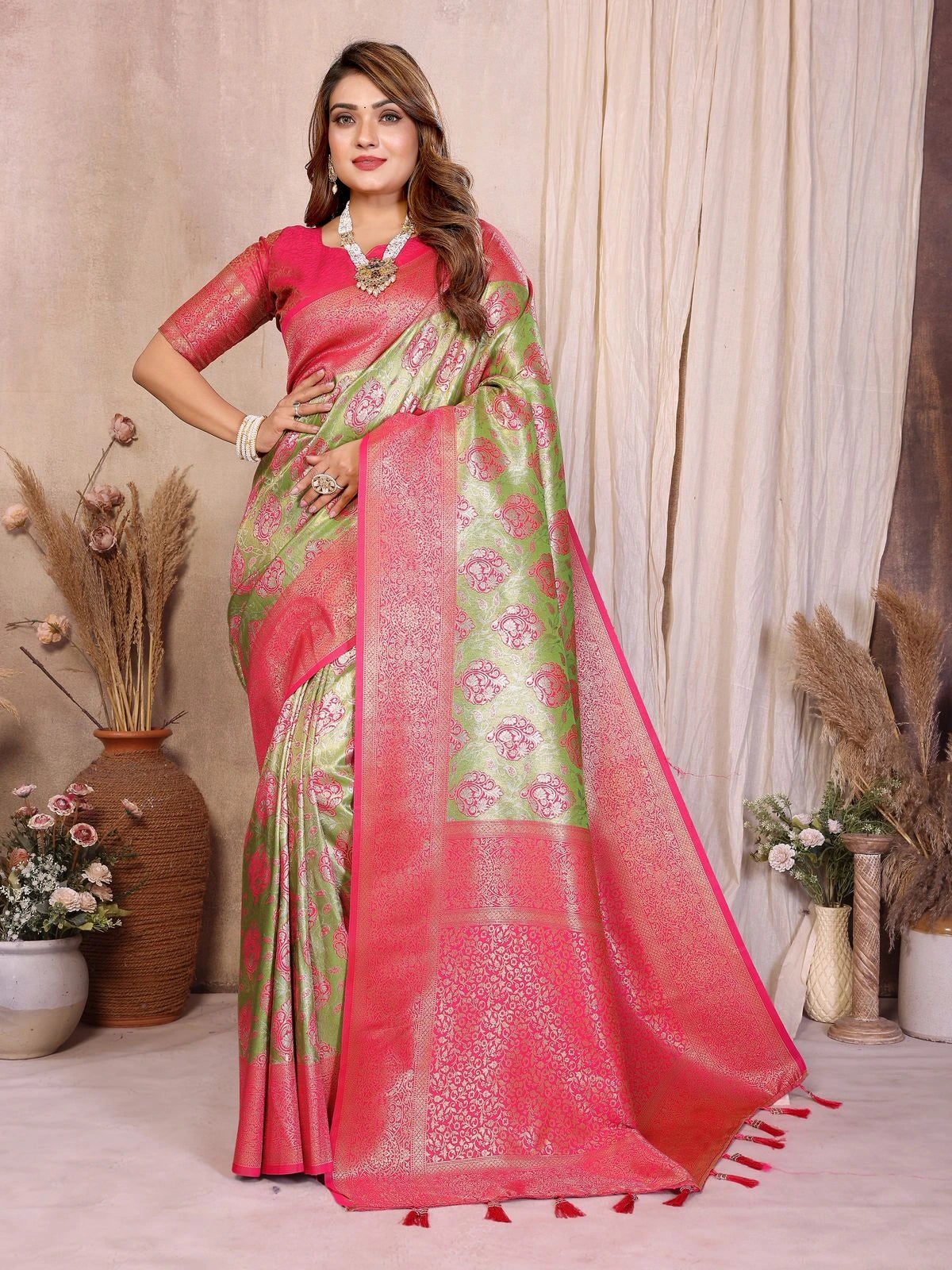 Woman wearing a pink and green saree with a neutral background