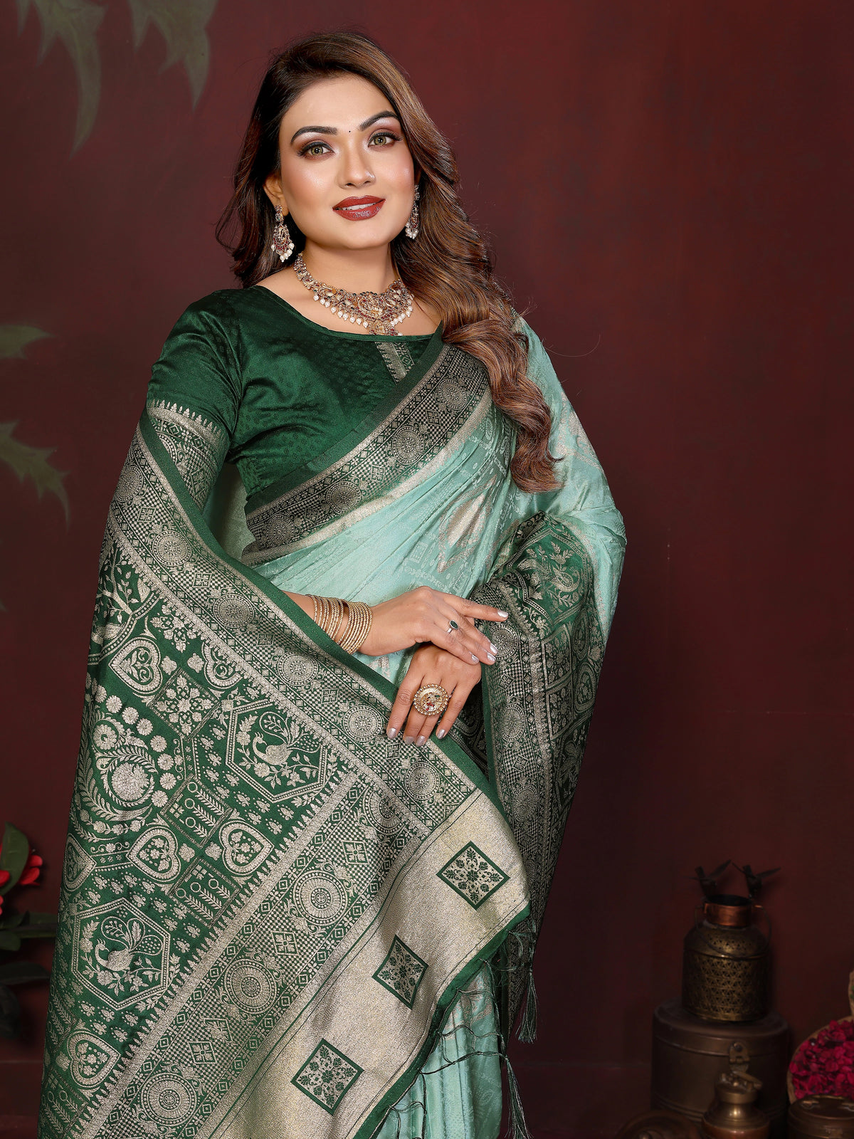 Woman wearing a green saree with a patterned border against a dark background