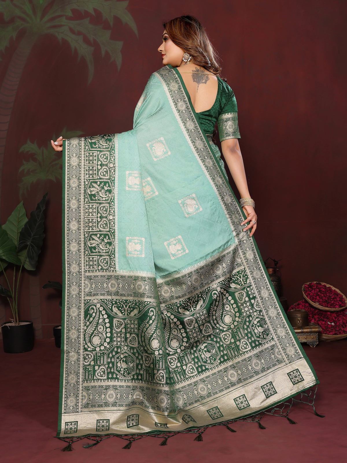 Woman wearing a green saree with a patterned border against a dark background