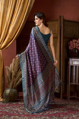 Woman wearing a patterned saree in an indoor setting with decorative elements.