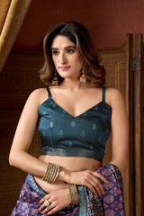 Woman wearing a dark blue saree with a floral pattern against a wooden background