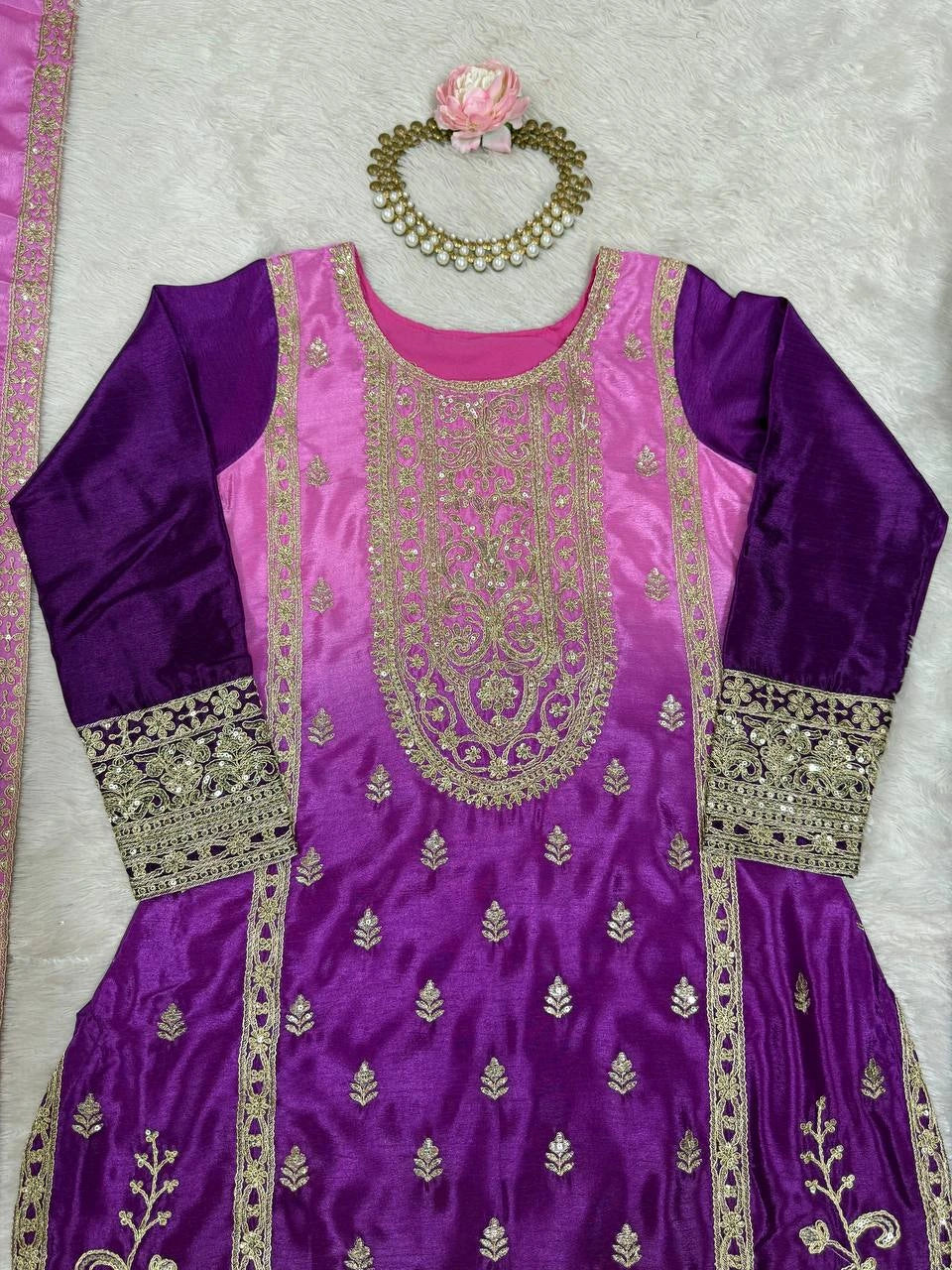 Purple and pink traditional outfit with gold embroidery on a light gray background