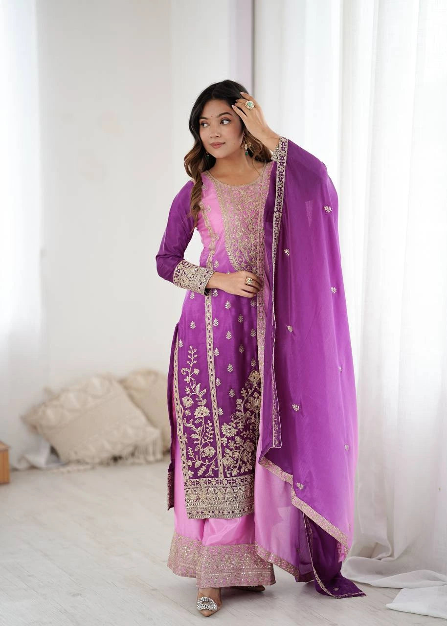 Woman wearing a traditional purple and pink outfit with intricate designs indoors.