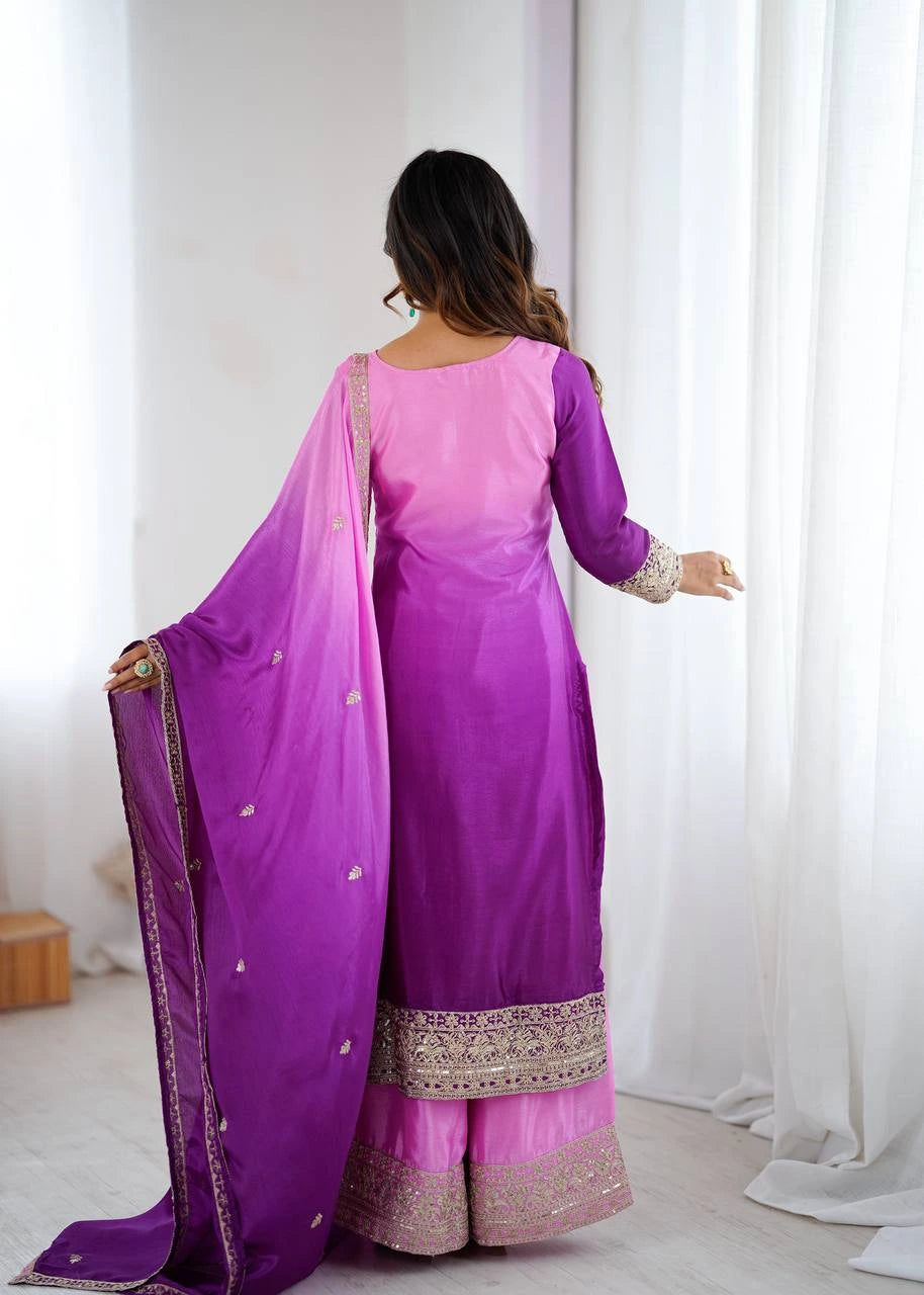 Woman wearing a purple and pink traditional outfit with a matching dupatta in a bright room.