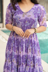 Person wearing a purple floral dress by a poolside