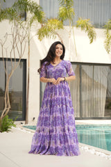 Woman in a purple dress standing by a pool with a building and trees in the background