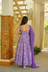 Woman in a purple dress with a matching scarf standing in a room with decorative elements.
