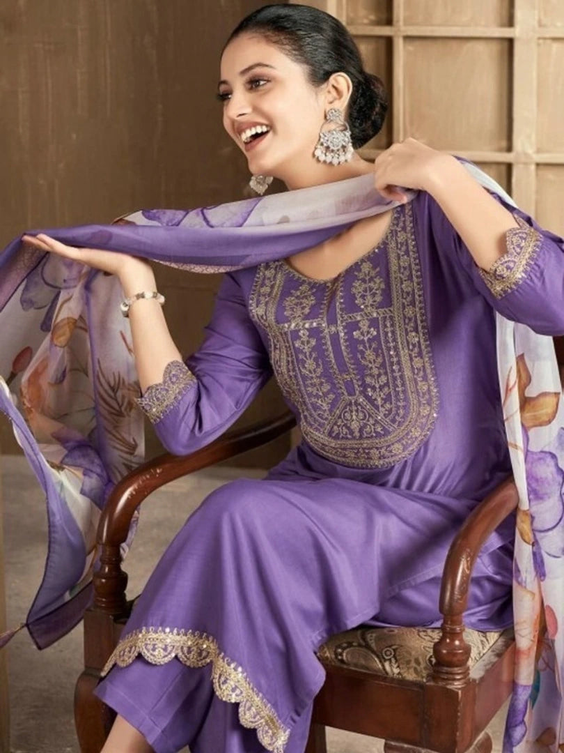 Woman in a purple embroidered outfit with a matching scarf, sitting on a wooden chair.