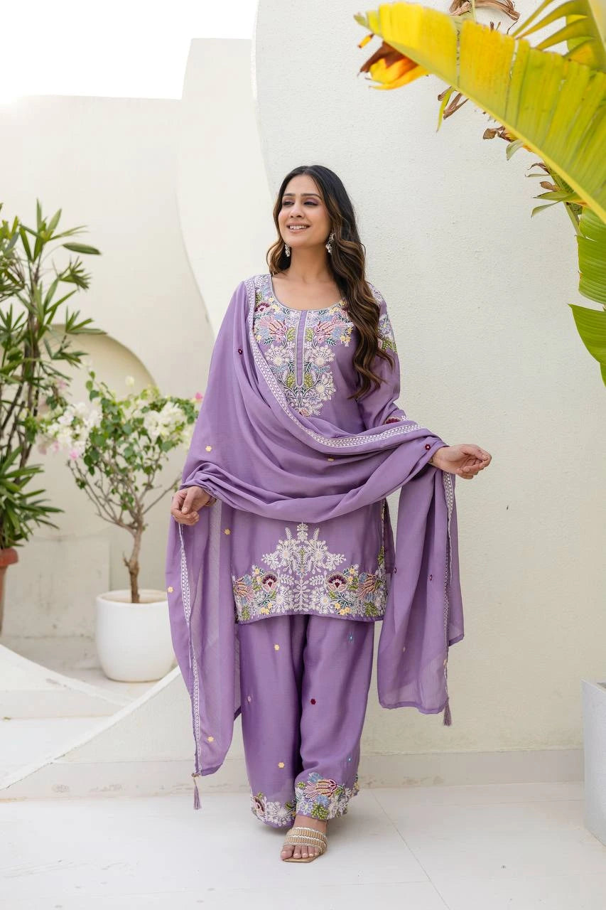 Woman in a purple traditional outfit with floral patterns in an outdoor setting.