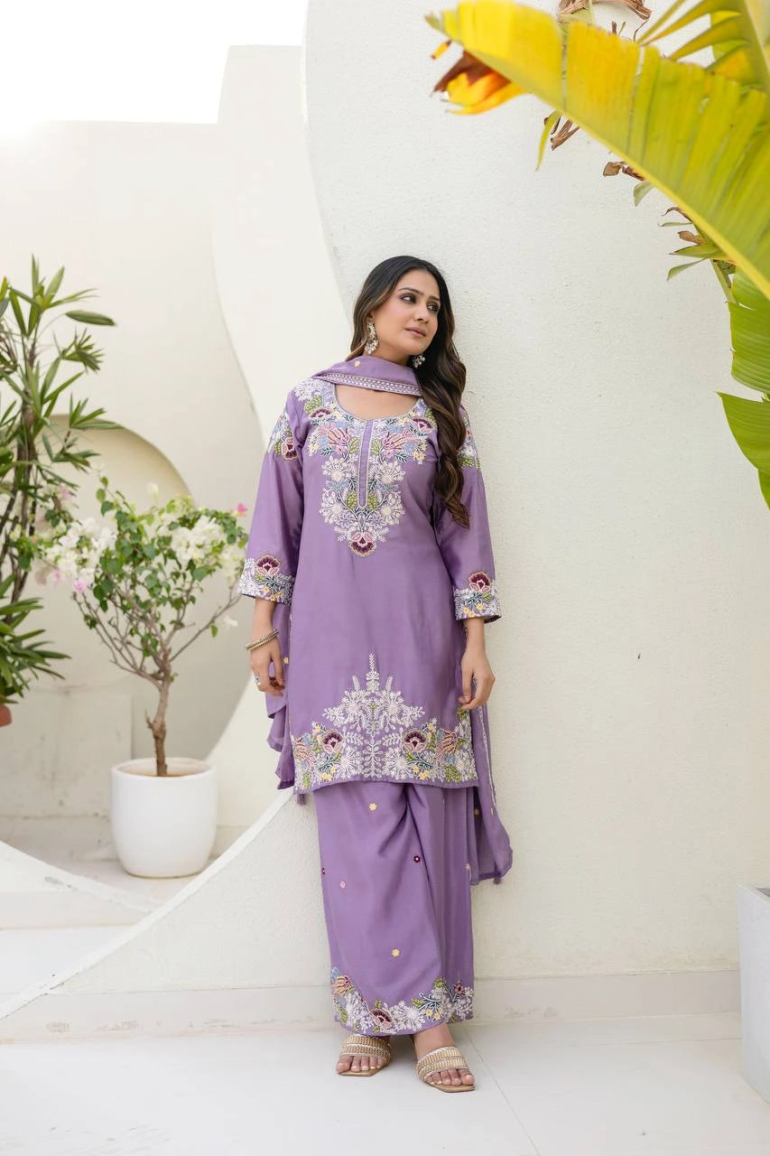 Woman wearing a purple embroidered outfit with plants in the background