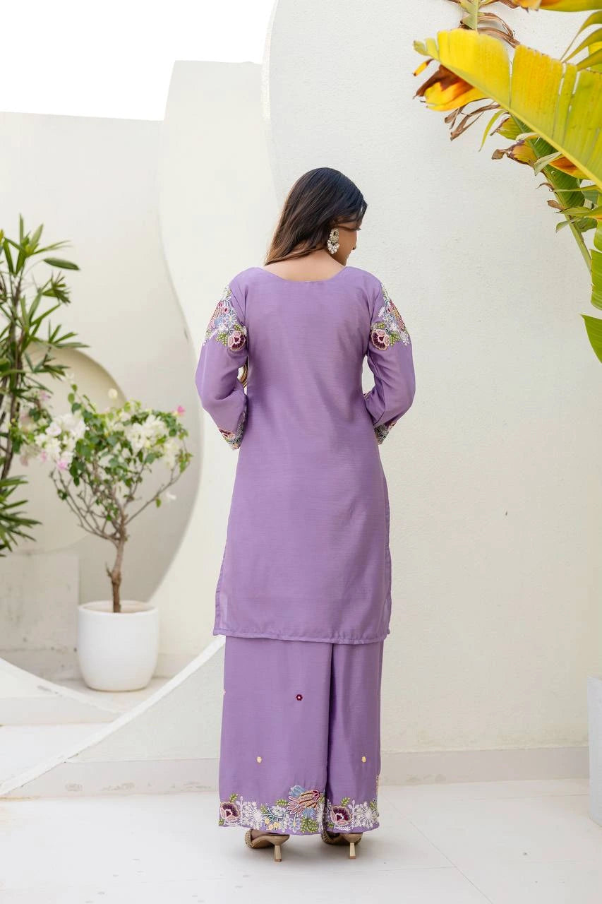Woman wearing a purple traditional outfit with floral embroidery in a minimalistic setting.