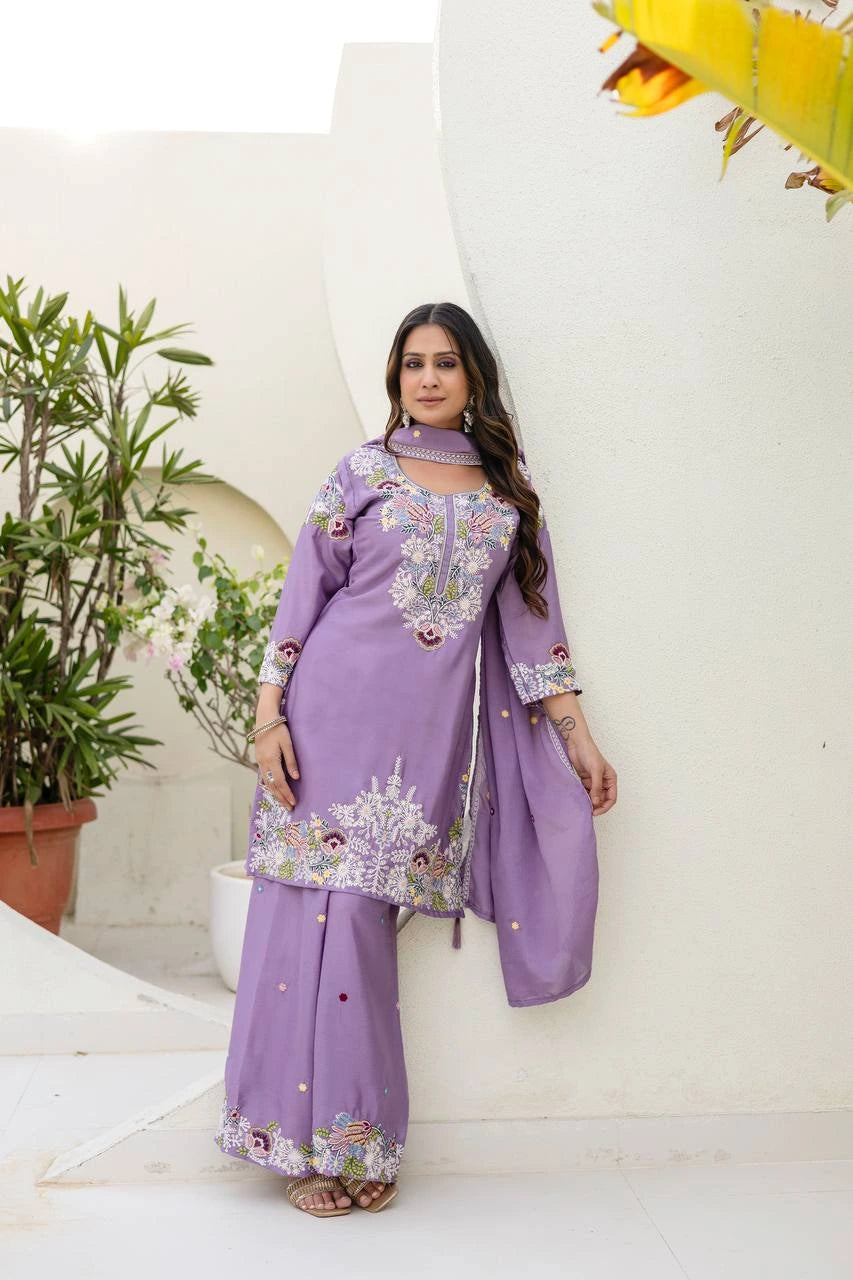 Woman wearing a purple traditional outfit with floral patterns indoors.