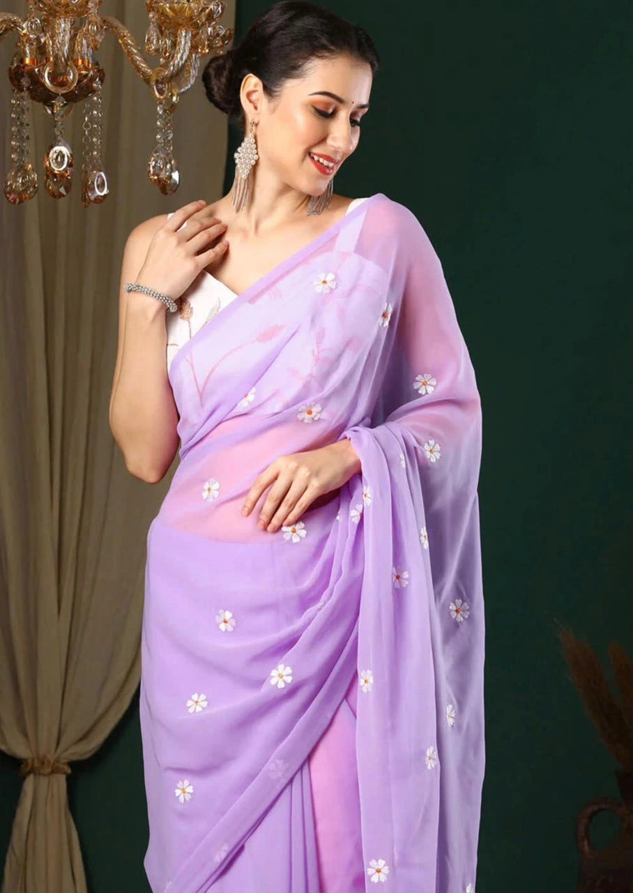 Woman wearing a light purple saree with white floral patterns against a dark background