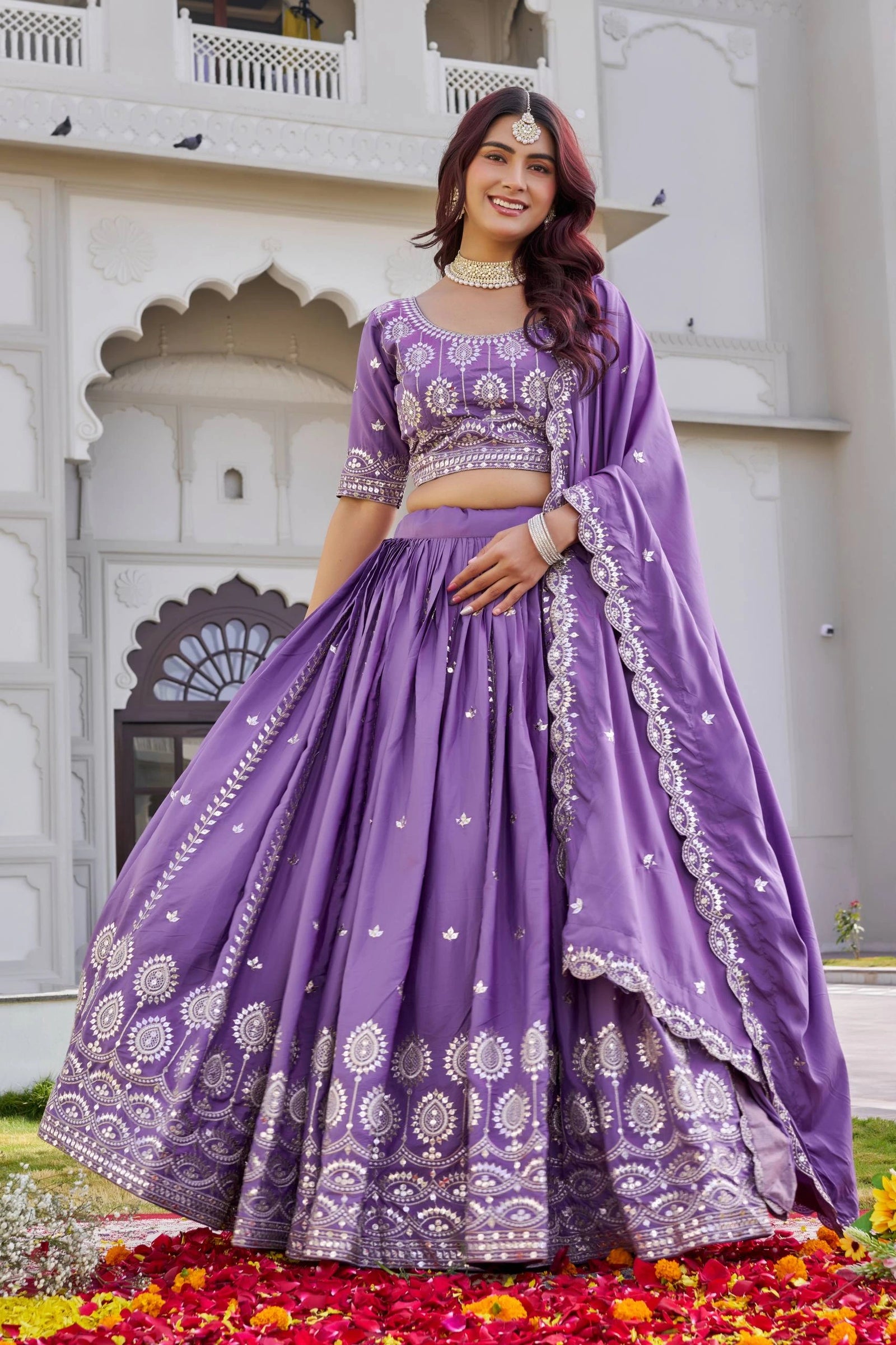 Woman in a purple traditional outfit standing in front of a white architectural background