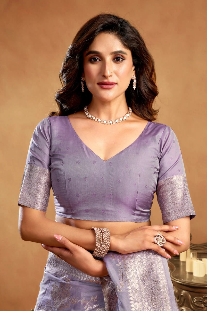 Woman wearing a purple saree with silver details against a beige background