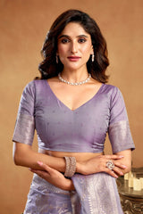 Woman wearing a purple saree with silver details against a beige background
