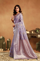 Woman in a purple saree standing in a decorated room with a brown background