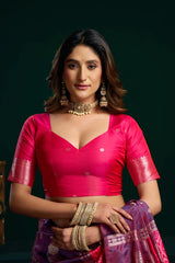 Woman in a pink traditional outfit with gold jewelry against a dark background
