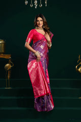Woman in a pink and purple saree standing on steps with a dark background