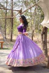Woman in a purple traditional outfit standing outdoors with trees in the background