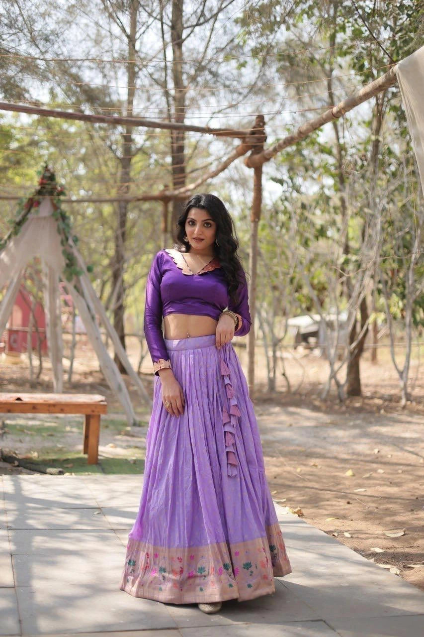 Woman in a purple outfit standing outdoors with trees in the background