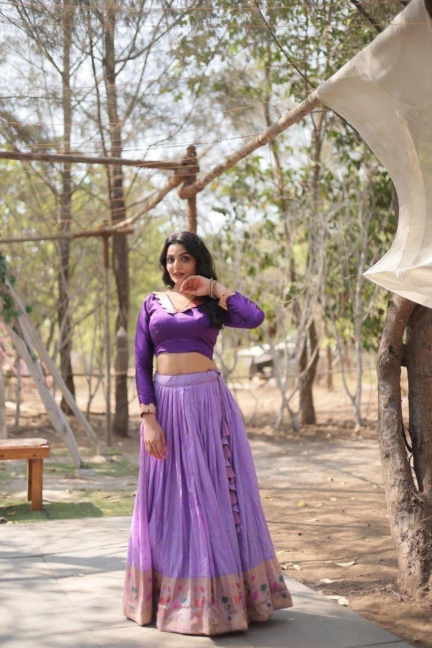 Woman in a purple traditional outfit standing outdoors with trees in the background