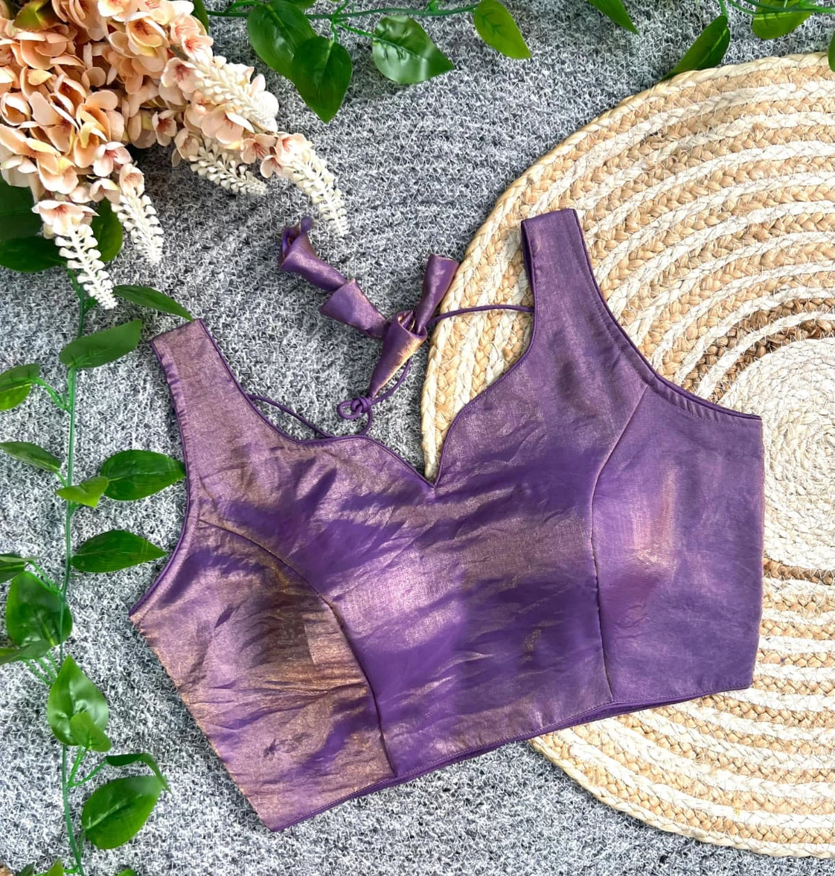 Purple bikini top on a textured surface with flowers and leaves