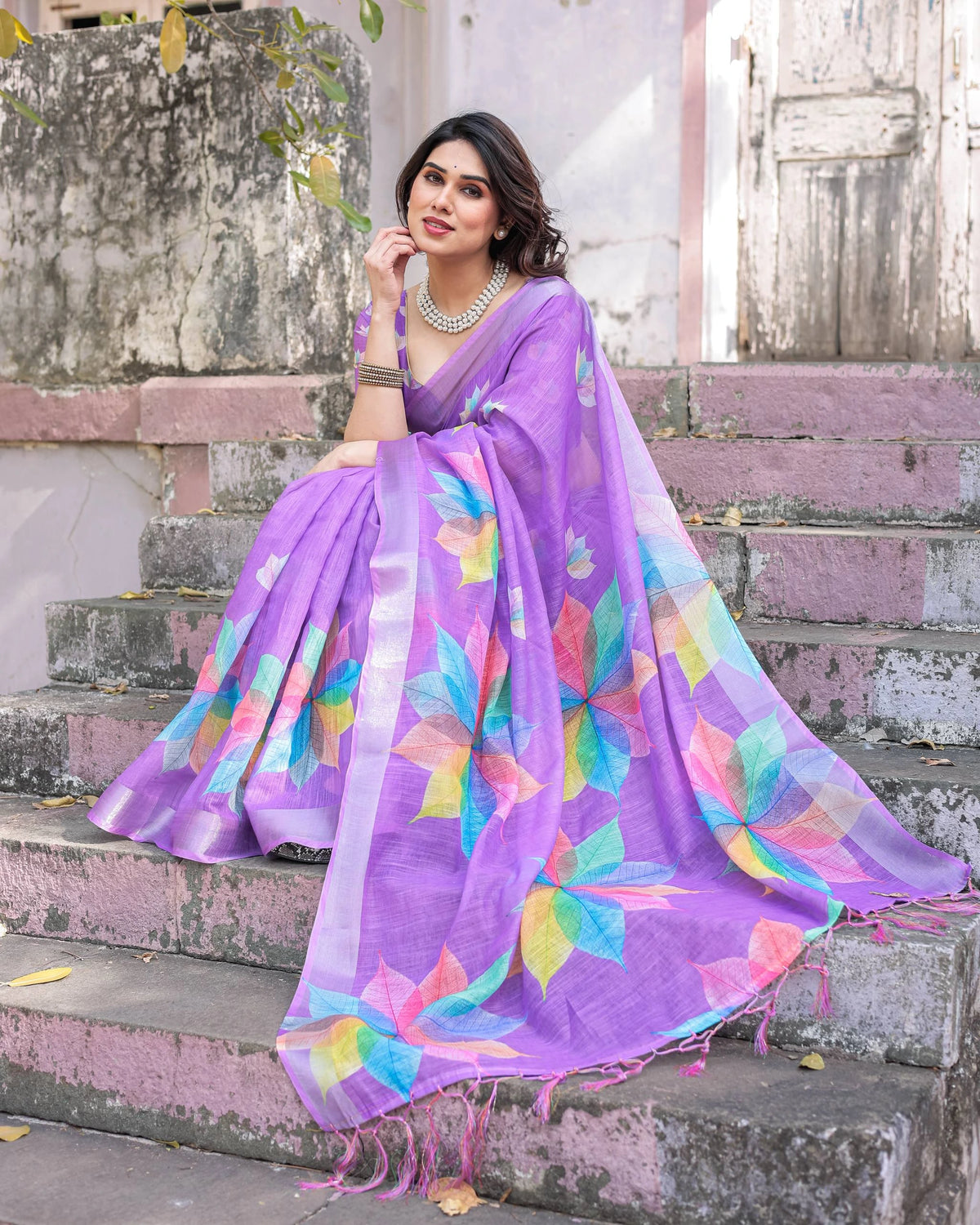 Woman wearing a colorful saree with a floral pattern on steps.