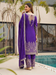 Woman in a purple traditional outfit standing by a pool with greenery around.