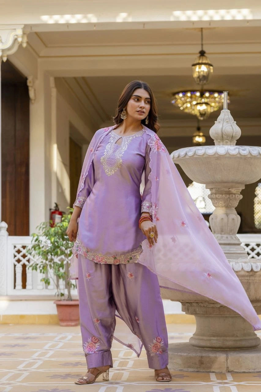 Woman in a lavender traditional outfit standing in an elegant indoor setting.