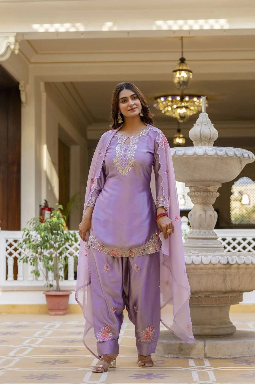 Woman in a lavender traditional outfit standing in an elegant indoor setting with decorative elements.