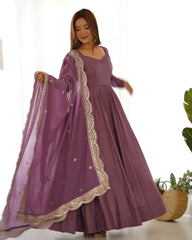 Woman wearing a purple dress with gold embroidery, holding a matching dupatta.