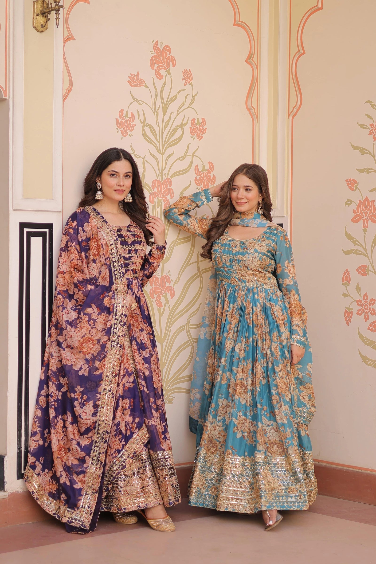 Two women wearing floral dresses standing in a decorated room.