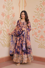 Woman in a floral dress standing against a decorative wall with floral patterns.