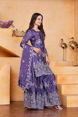 Woman in a purple traditional outfit standing in a decorative indoor setting.