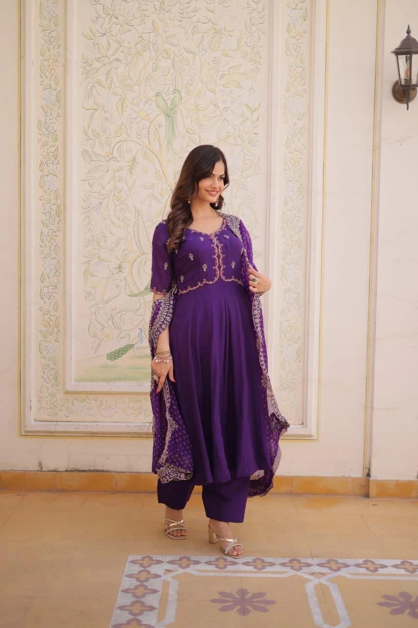Woman wearing a purple traditional outfit with gold embroidery in an indoor setting.