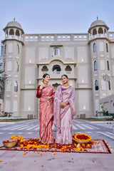 Two women in traditional sarees standing in front of a building with decorative elements on the ground.