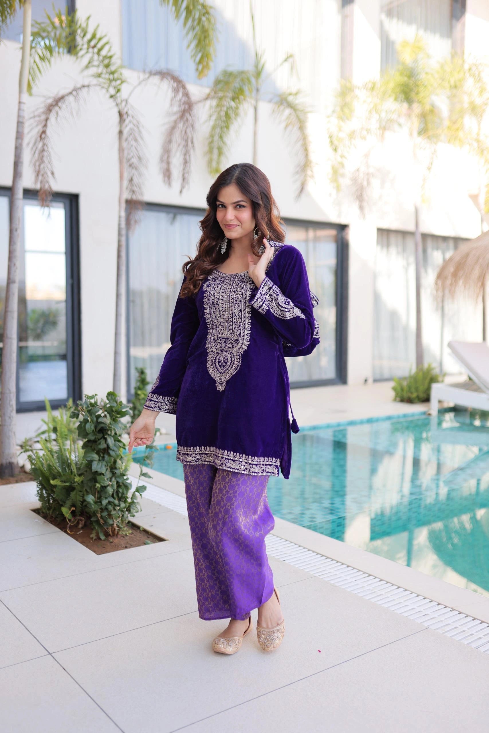 Woman in a purple outfit standing by a pool with a modern building in the background